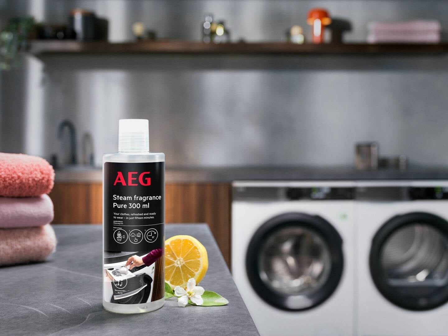 Flacon AEG Steam fragrance Pure 300 ml pose devant un lave-linge AEG, accessoire ProSteam
